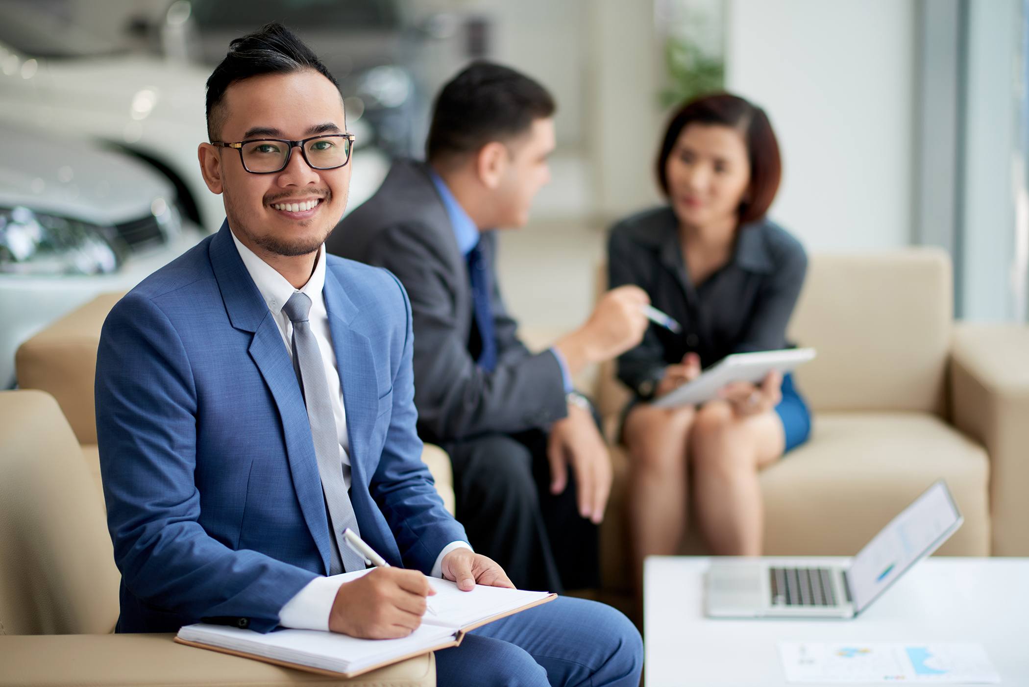 Image of a finance manager, smiling and writing notes while dealing with a client.