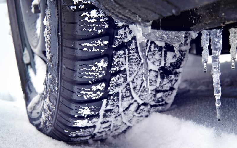 Icicles on a car with winter tires and good pattern in snow, safety driving