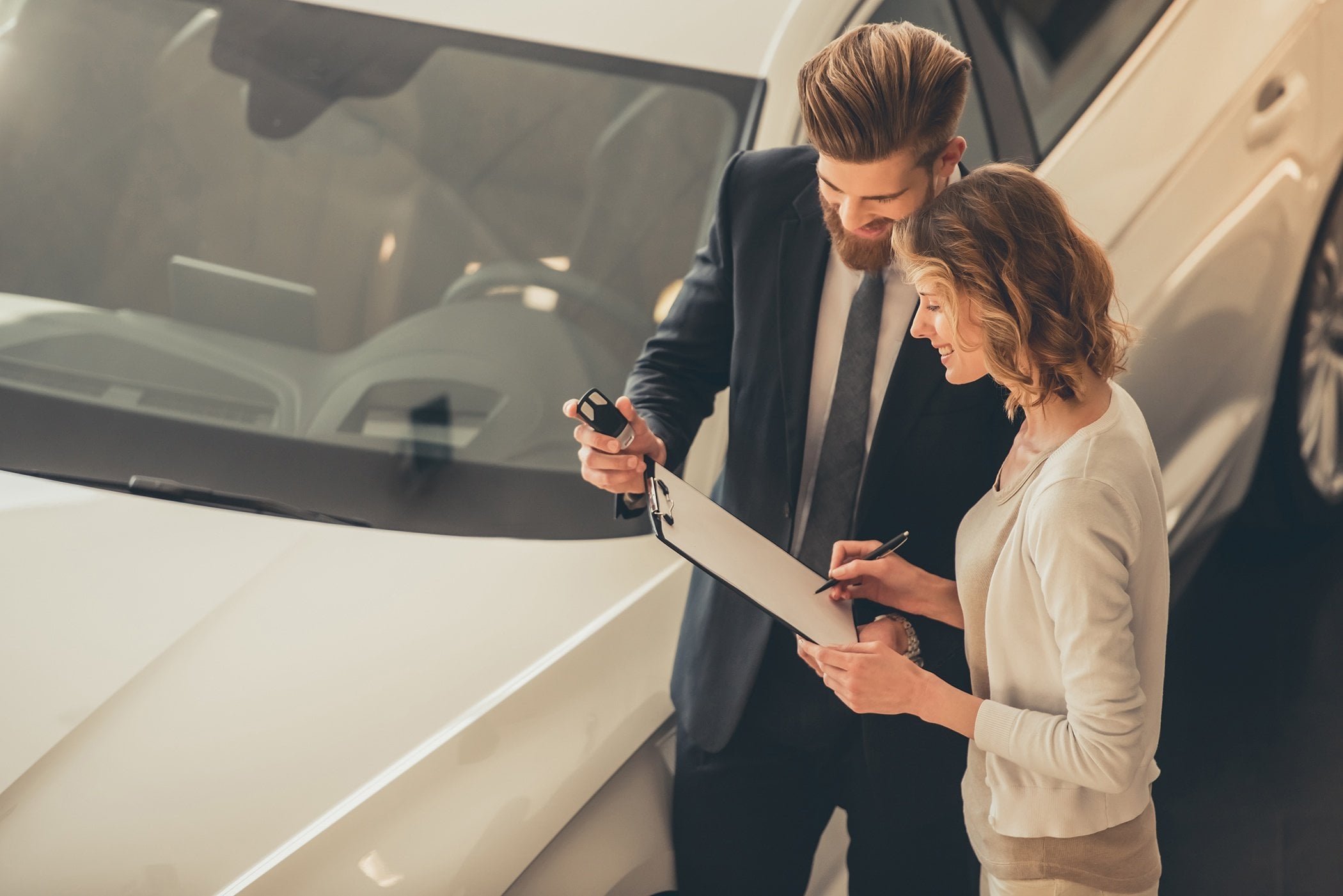 Image of a sales person, helping a customer at the dealership with signing a contract for a vehicle.